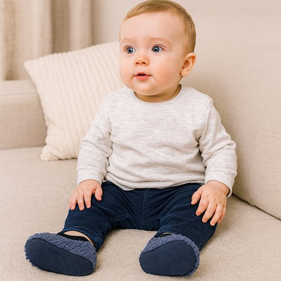 Bambin assis avec chaussons bébé antidérapants bleus