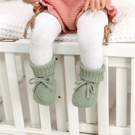 Fillette assise avec chausson bébé confort vert