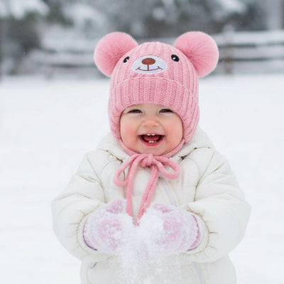 Fillette joue dans neige avec bonnet bebe ourson joyeux rose