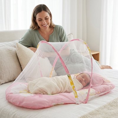 Maman regarde bébé dans lit de voyage pour bébé ultra léger rose