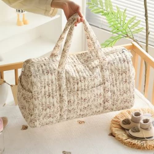 Mère dépose sac a langer matelassé fleuri dans bassinette
