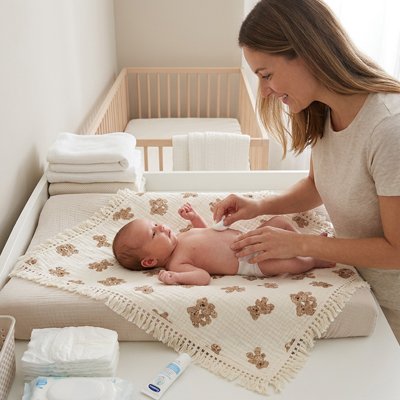 Mère nettoie bébé sur lange d emmaillotage ourson mignon