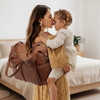 Mère-porte-sur-dos-sac-à-dos-à-langer-sophistiqué-et-enfant-dans-ses-bras