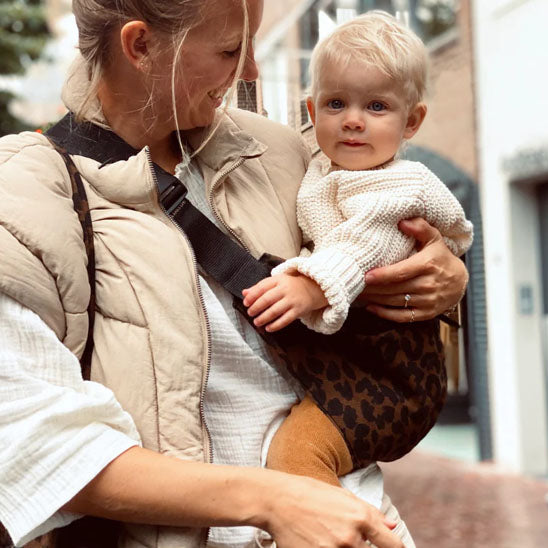 Mère-sourit-à-enfant-dans-écharpe-portage-léopard