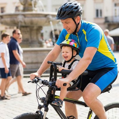 Père avec enfant sur porte bebe velo sécurisé