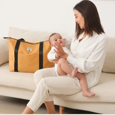 Femme-assise-à-côté-de-sac-a-langer-décontracté-et-bébé-dans-ses-bras