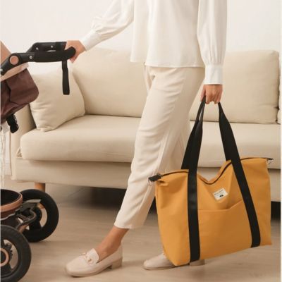 Femme-pousse-poussette-avec-sac-a-langer-décontracté-dans-une-main